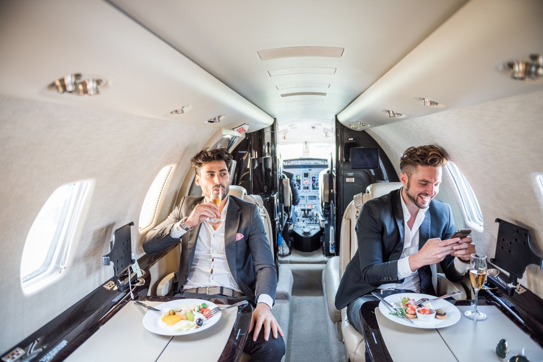 two men enjoying dinner and champagne on a private jet
