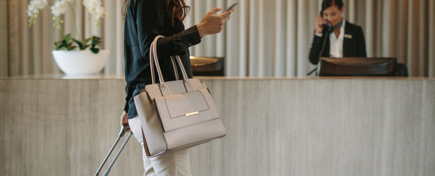 woman with her luggage and bag walking through a lobby