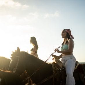 group of woman horseback riding on the beach