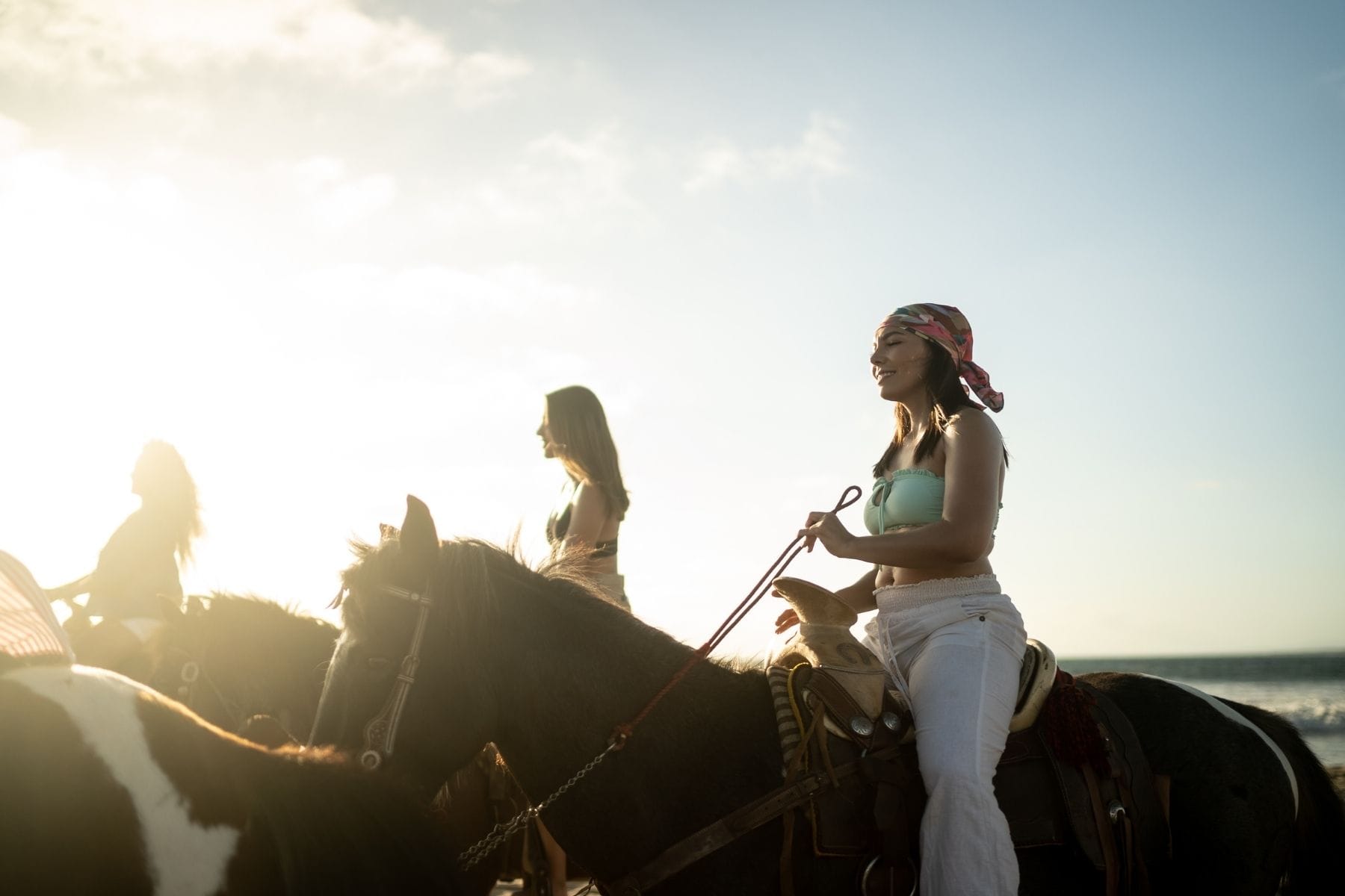 group of woman horseback riding on the beach