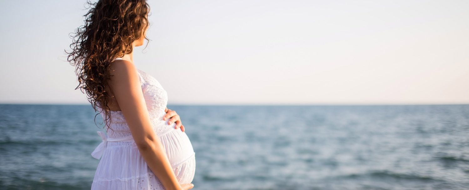 Young pregnant woman walking on the beach.