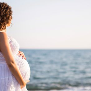 Young pregnant woman walking on the beach.