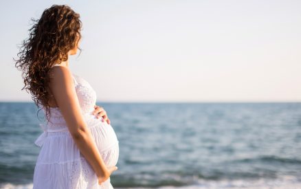 Young pregnant woman walking on the beach.