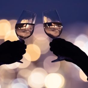Couple drinking wine together against a city lights view.