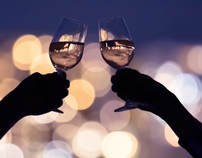 Couple drinking wine together against a city lights view.