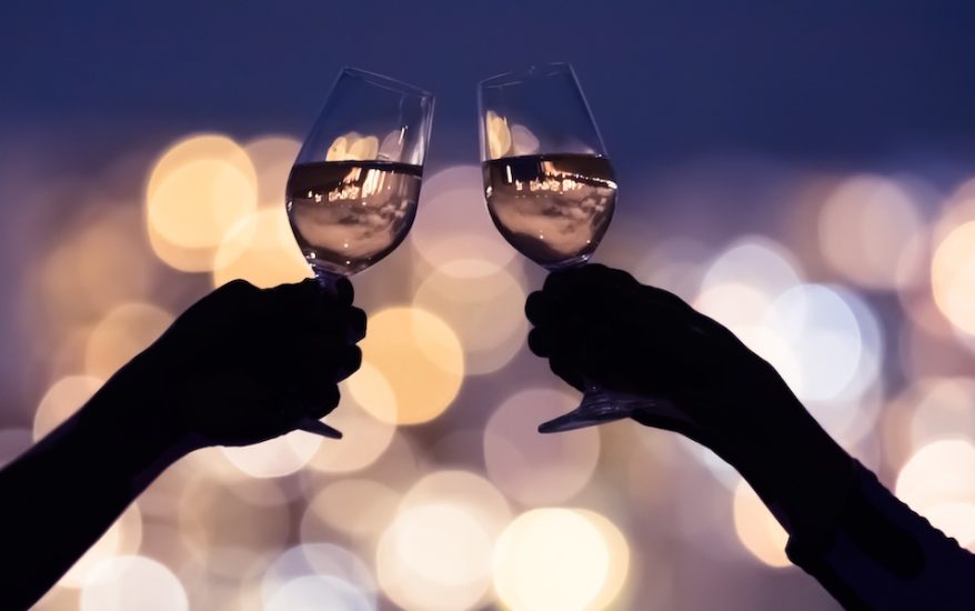 Couple drinking wine together against a city lights view.
