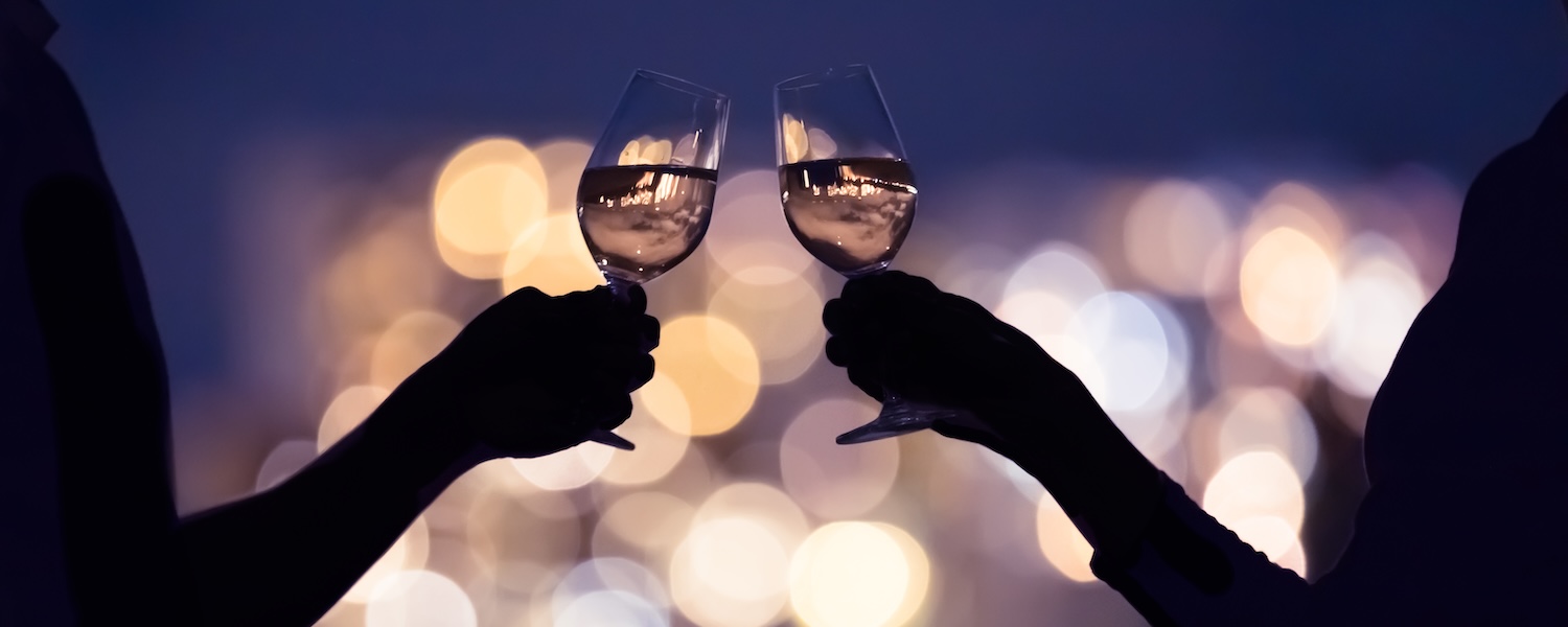 Couple drinking wine together against a city lights view.
